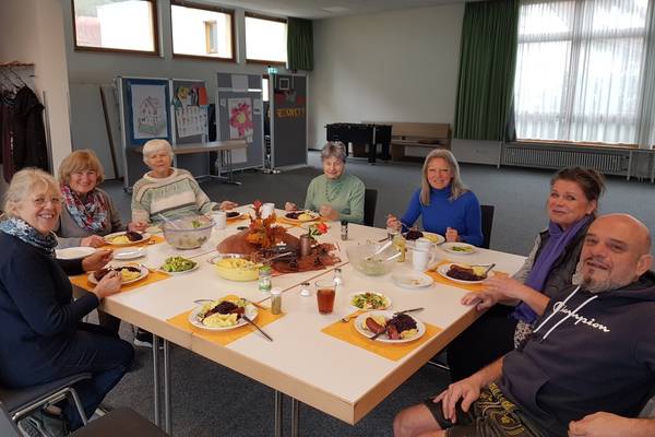Menschen die gemeinsam um einen gedeckten Tisch sitzen