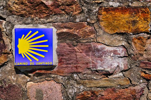 Ein Foto von einem blauen Schild mit gelber Aufschrift Camino de Santiago.